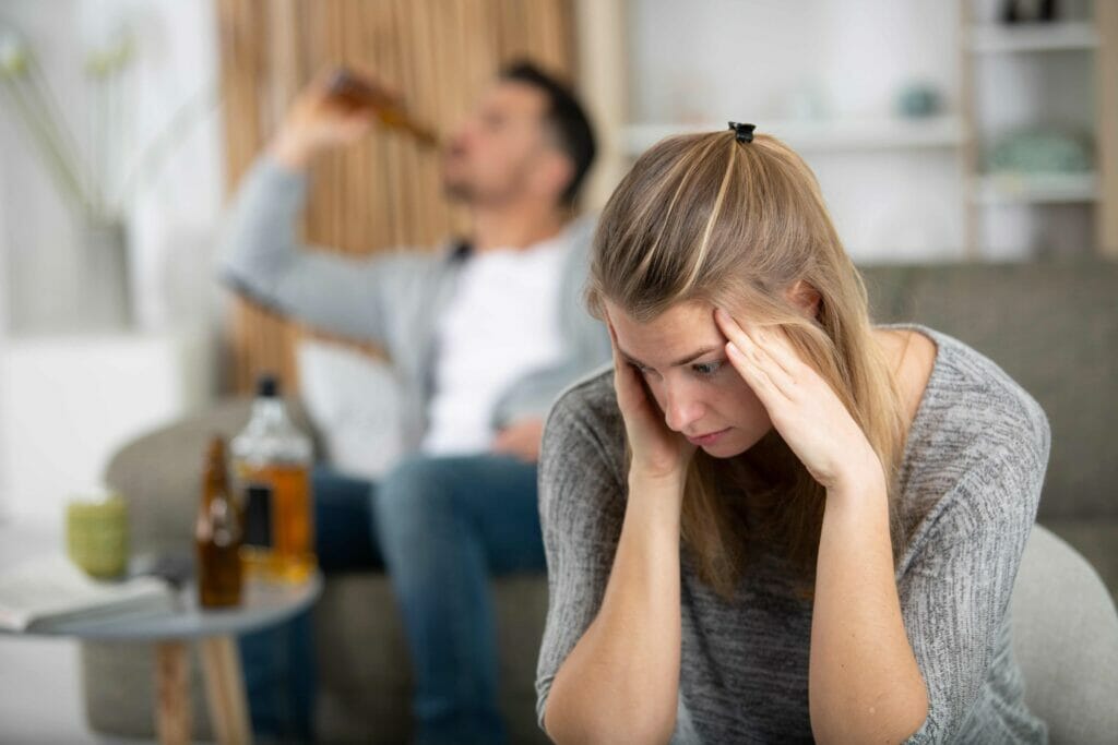 depressed woman next to alcoholic husband