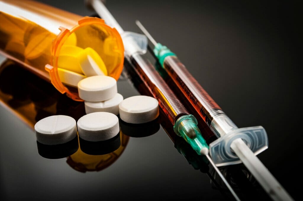 prescription opioids next to heroin syringe